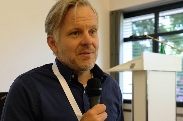 Der frühere Leiter der Jugendherberge Köln -Riehl, Steffen Minas, spricht als jetziges Vorstandsmitglied des Deutschen Jugendherbergswerks Rheinland das erste Grußwort. Man sieht ihn mit Mikrofon.
