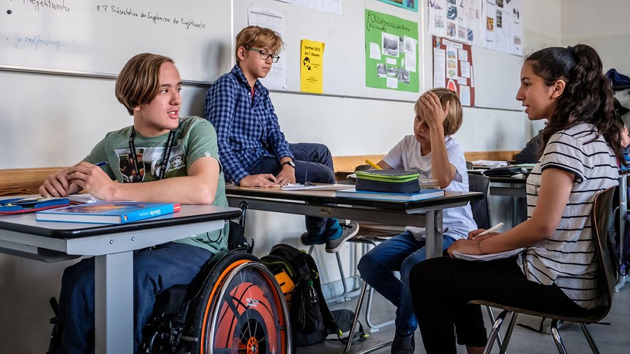 Klassenzimmer Vier Schüler sitzen beisammen in einem Klassenzimmer.