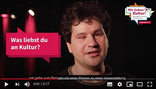 Screenshot von einem Youtube-Film. Ein Mann schaut in die Kamera. Neben im steht eine Sprechblase mit dem Text „Was liebst du an Kultur?“