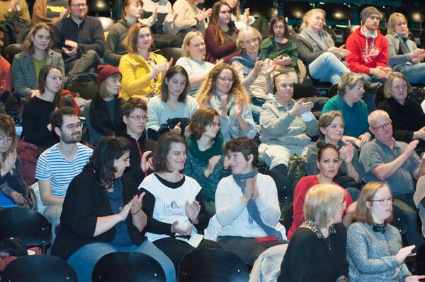 Publikum in gut gefülltem Theatersaal beim Applaus