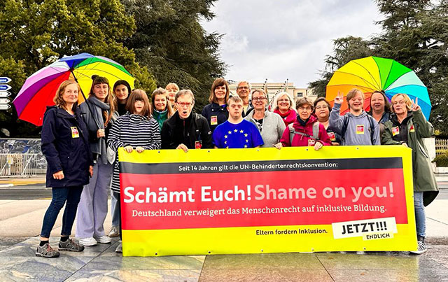 Rund zwanzig Erwachsene und Jugendliche mit und ohne Behinderung stehen hinter einem Banner mit der Aufschrift: Seit 14 Jahren gilt die Behindertenrechtskonvention: Schämt Euch! Deutschland verweigert das Menschenrecht auf inklusive Bildung. Eltern fordern Inklusion. Jetzt! Endlich!